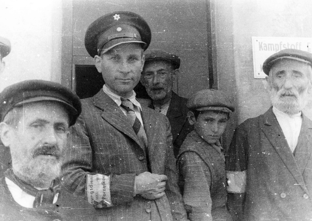 Tomaszow Mazowiecki a ghetto policeman stands with Jews